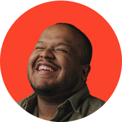 Smiling man with closed eyes against a red circular background.